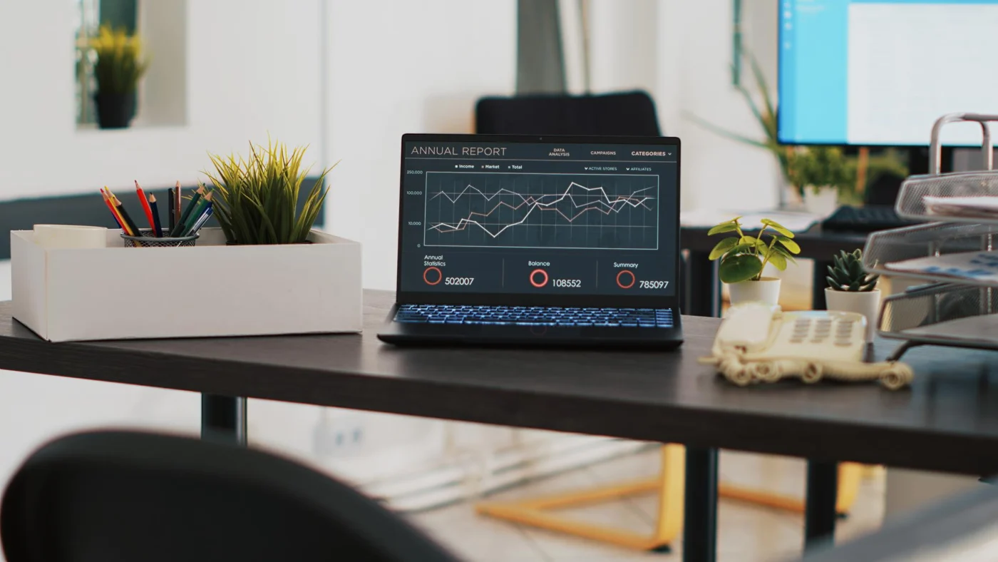 A laptop showing a financial report on a desk