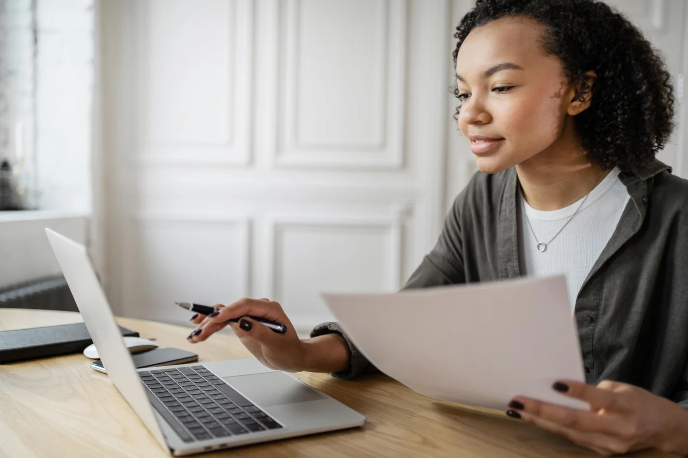 A contractor reviewing a contract beside a laptop with documents