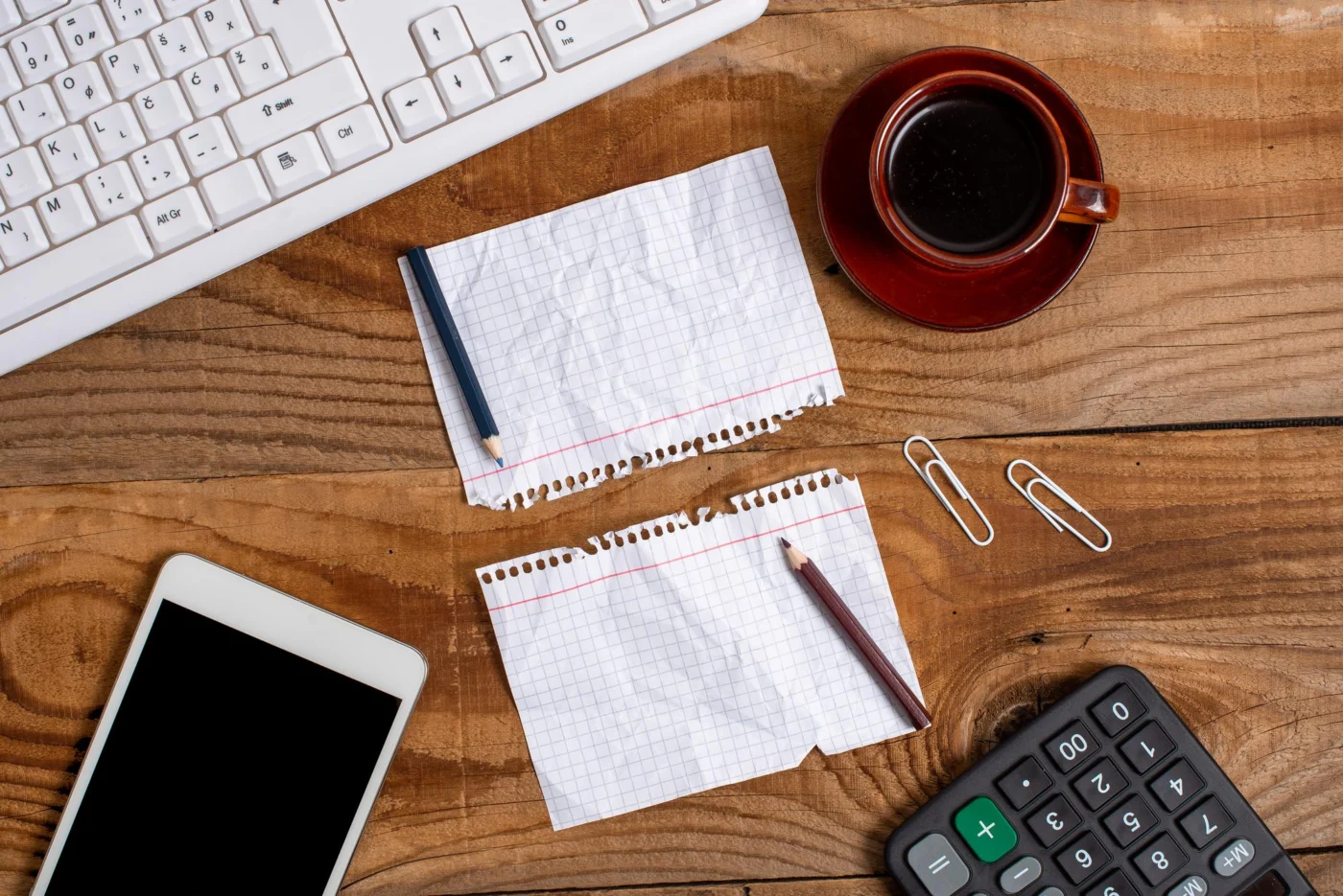 A phone, calculator and business receipts laid out on a desk