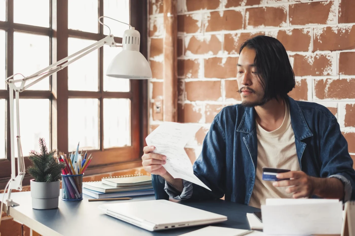 A small business owner reviewing paperwork and finances at a laptop