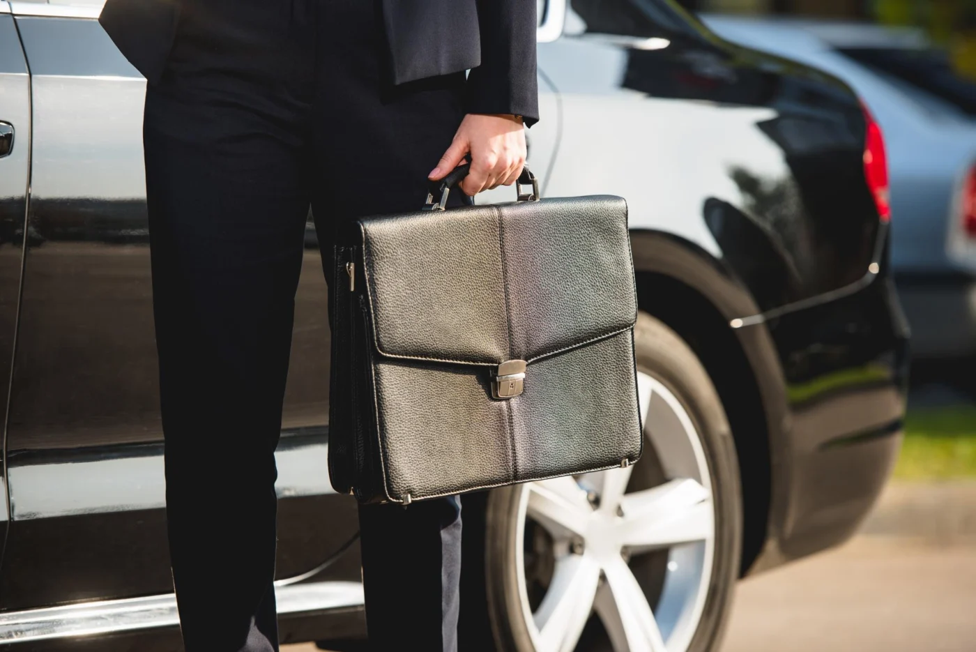 A director getting into an electric company car with a laptop bag