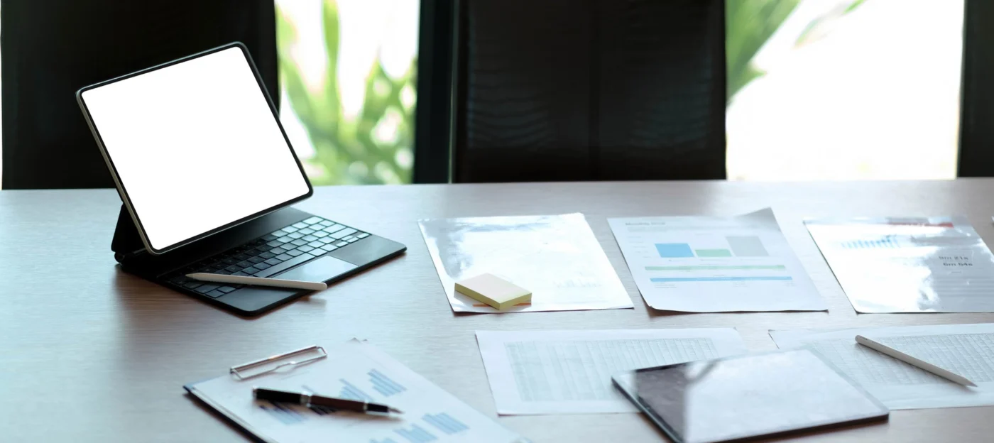Company incorporation documents beside a laptop on a desk